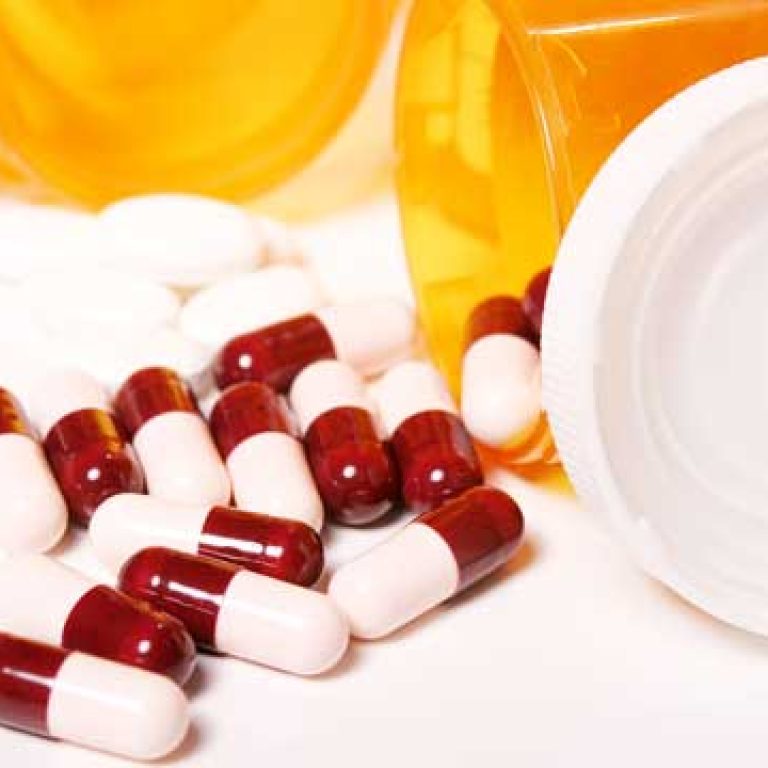 A drug rehab center's medicine bottle with pills and drug addiction treatment on a white surface.