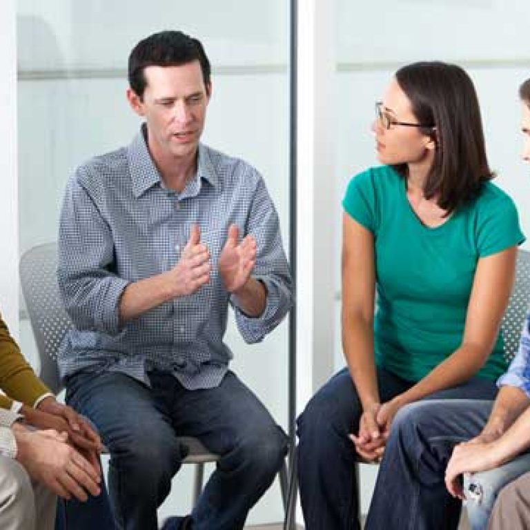 A group of people sitting in a circle talking during a drug addiction treatment.